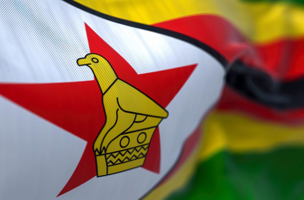 Close-up view of the Zimbabwe national flag waving in the wind. The Republic of Zimbabwe is a country located in Southeast Africa. Fabric textured background. Selective focus. 3D illustration