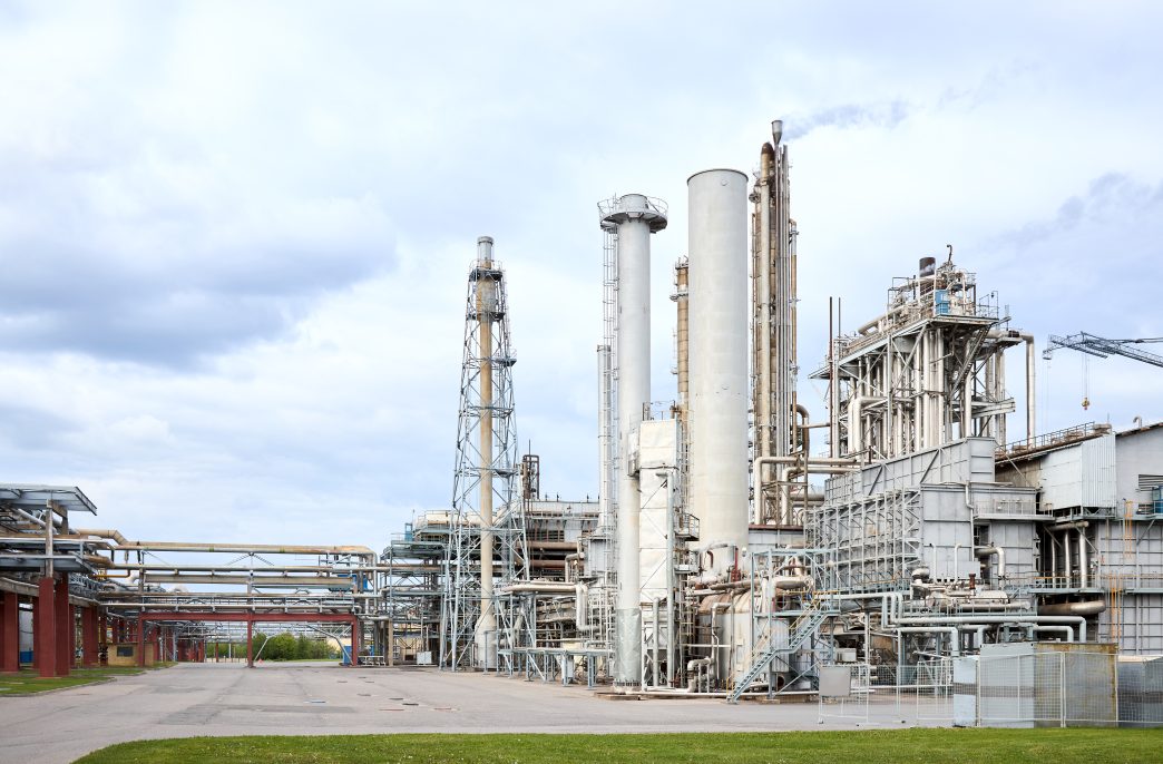Large-capacity ammonia production workshop. Exterior of modern petrochemical plant with reactors spherical gasholder and converters under heavy sky with copyspace.
