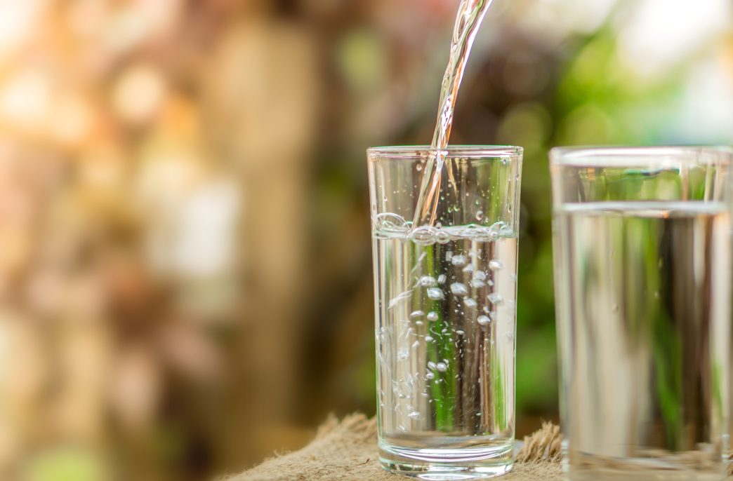 Pouring fresh water on drinking glass over nature sunlight morning ,freshness concept background