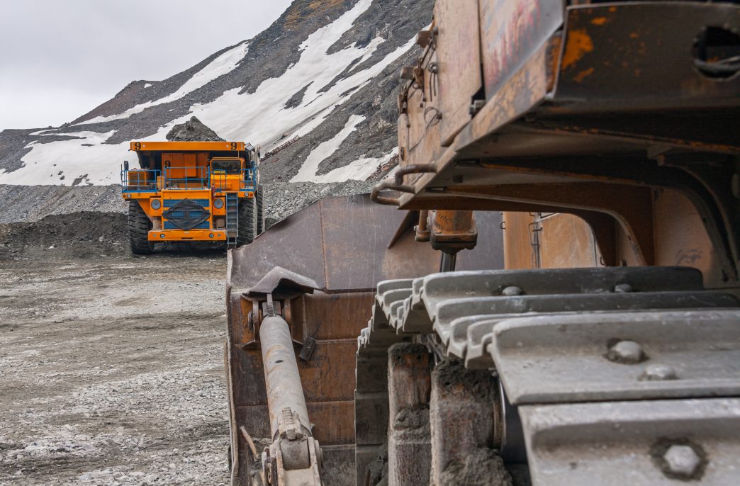 Powerful quarry bulldozer and gigat dump truck operating in the apatite mine in the Murmansk region. Mineral mining in the highlands.