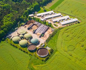 Aerial view of biogas plant near farm in countryside. Ecological renewable energy production from agricultural waste. Modern agriculture from above.
